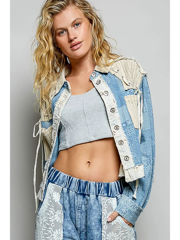 Woman wearing a denim outfit with a gray crop top against a plain background