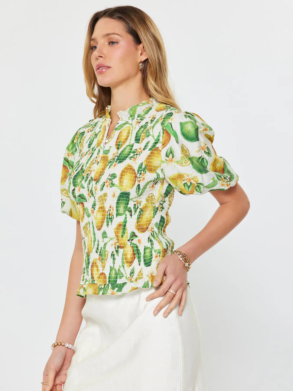 Woman wearing a pineapple patterned blouse against a white background