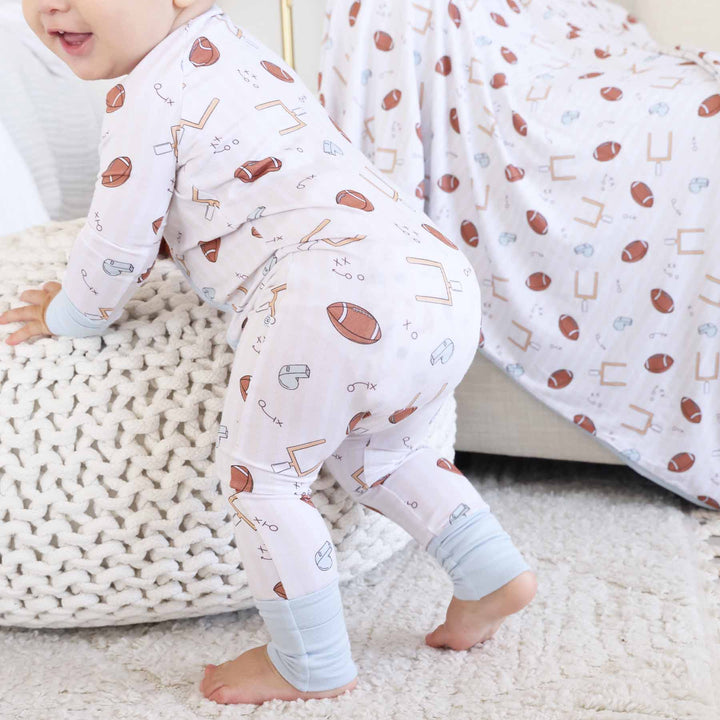 Child wearing pajama pants with sports-themed pattern on a soft surface