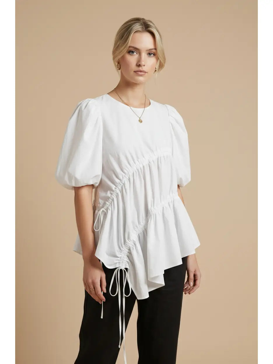 Woman wearing a white blouse with puff sleeves against a beige background