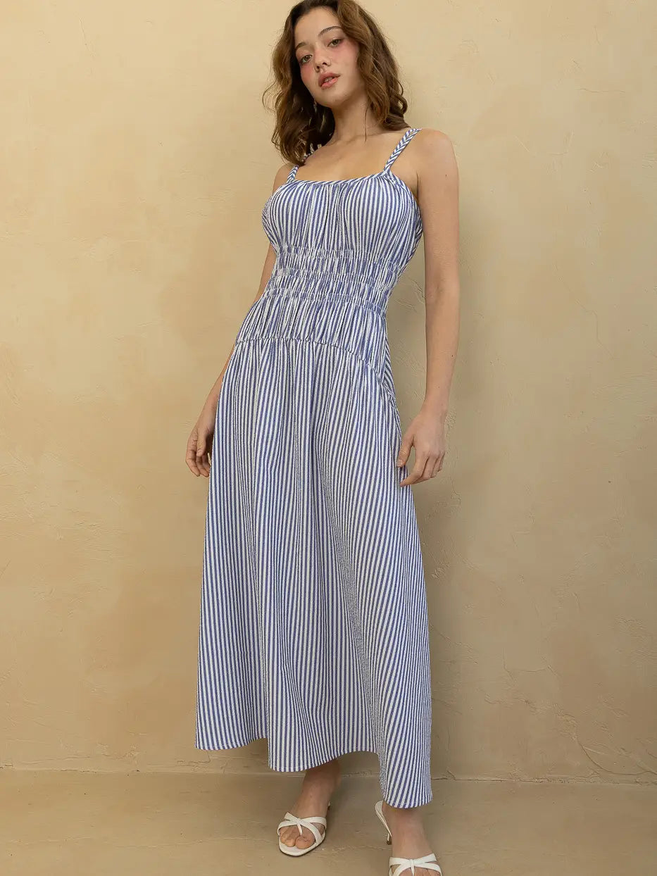 Woman wearing a blue and white striped dress against a beige background