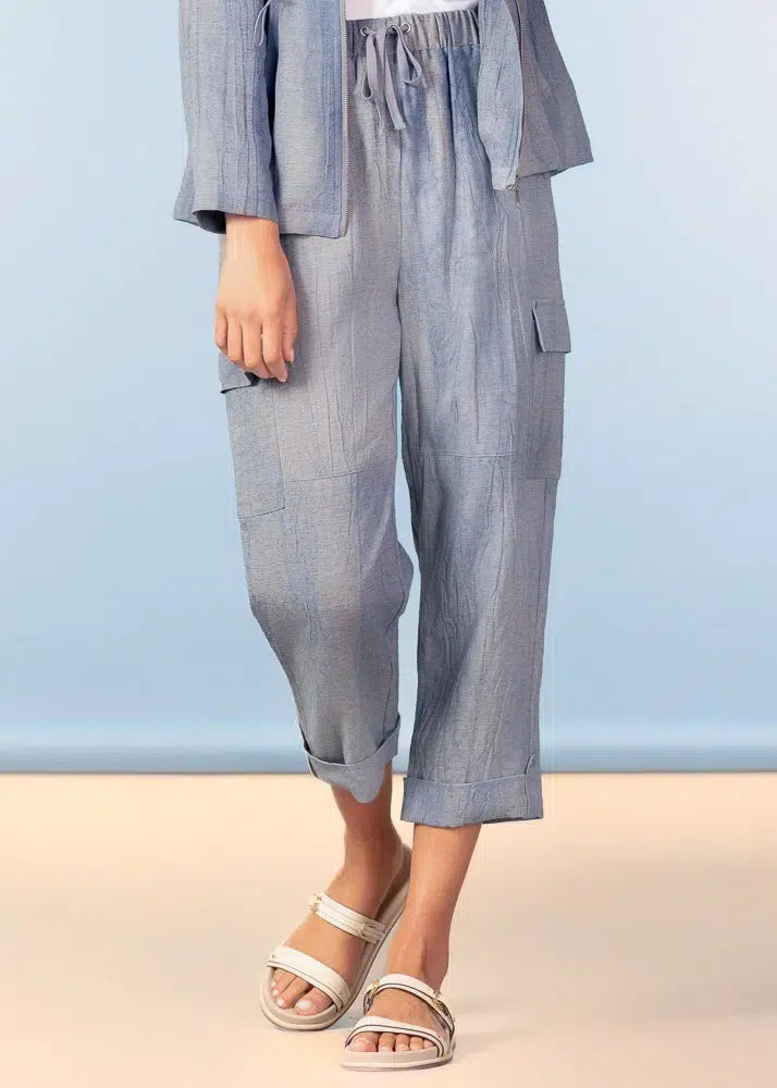 Person wearing a light blue outfit with pants and a jacket against a light blue background