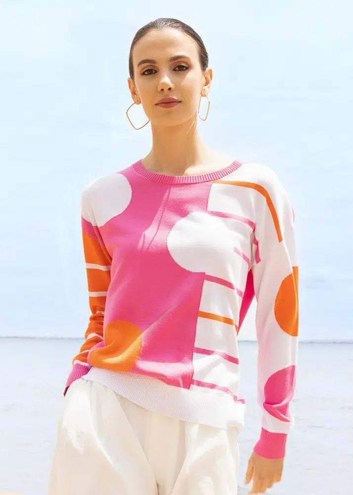 Woman wearing a colorful polka dot sweater against a clear blue sky.