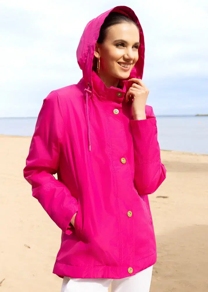 Woman wearing a bright pink raincoat on a beach