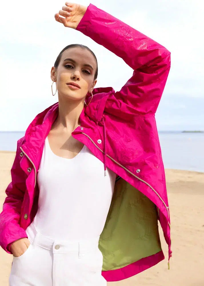 Woman wearing a bright pink jacket on a beach
