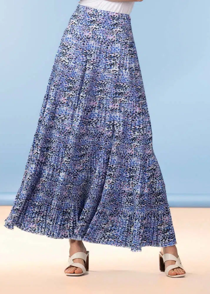 Long blue floral skirt worn by a person on a beach with a light blue background