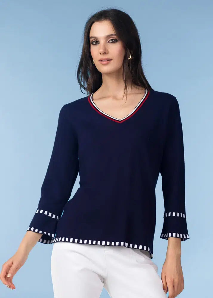 Woman wearing a navy blue sweater with white trim against a light blue background
