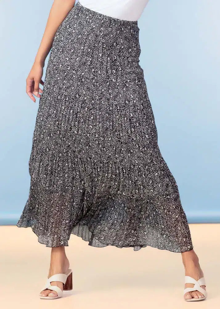 Person wearing a patterned skirt on a beach with a blue sky background