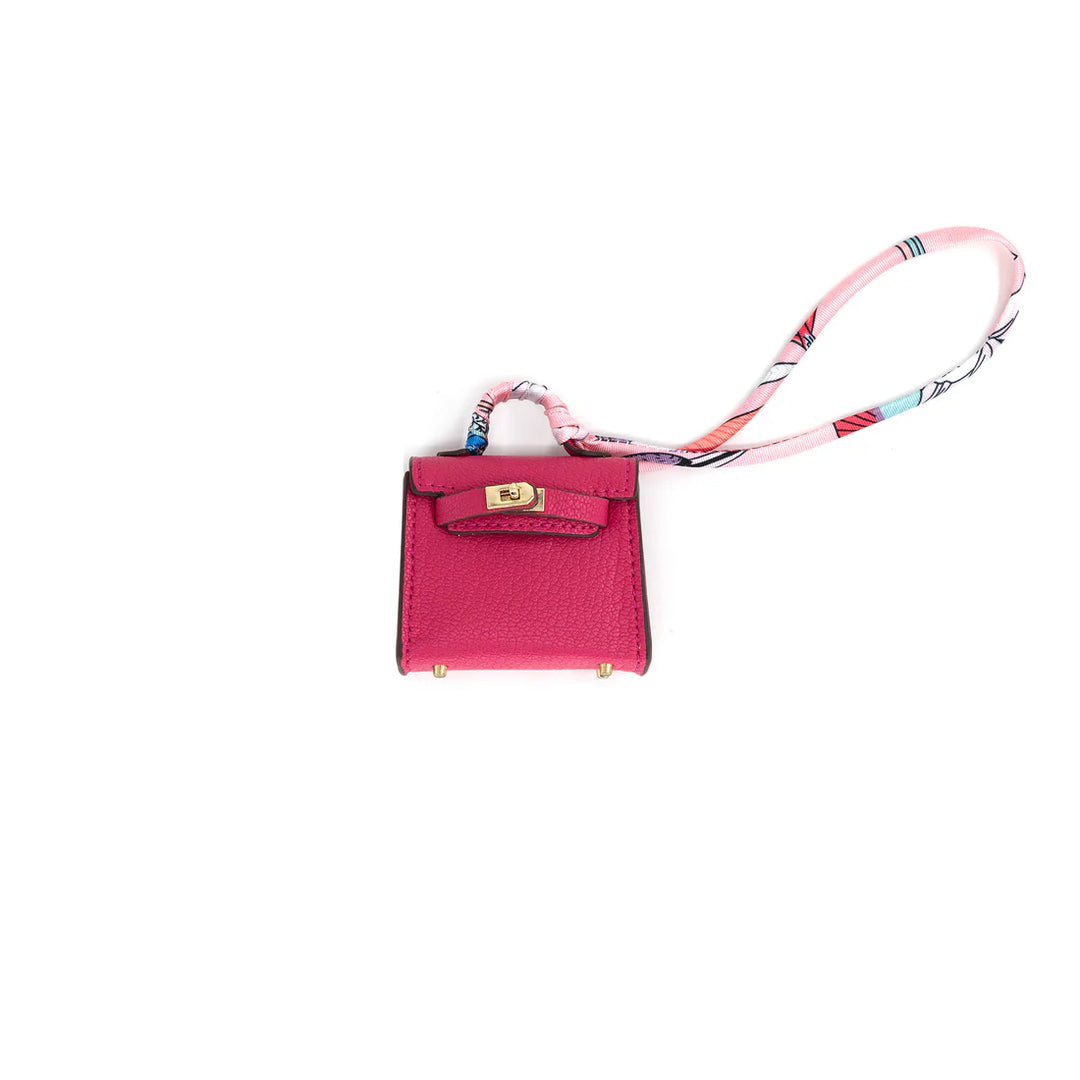 Pink handbag charm with a colorful strap on a white background