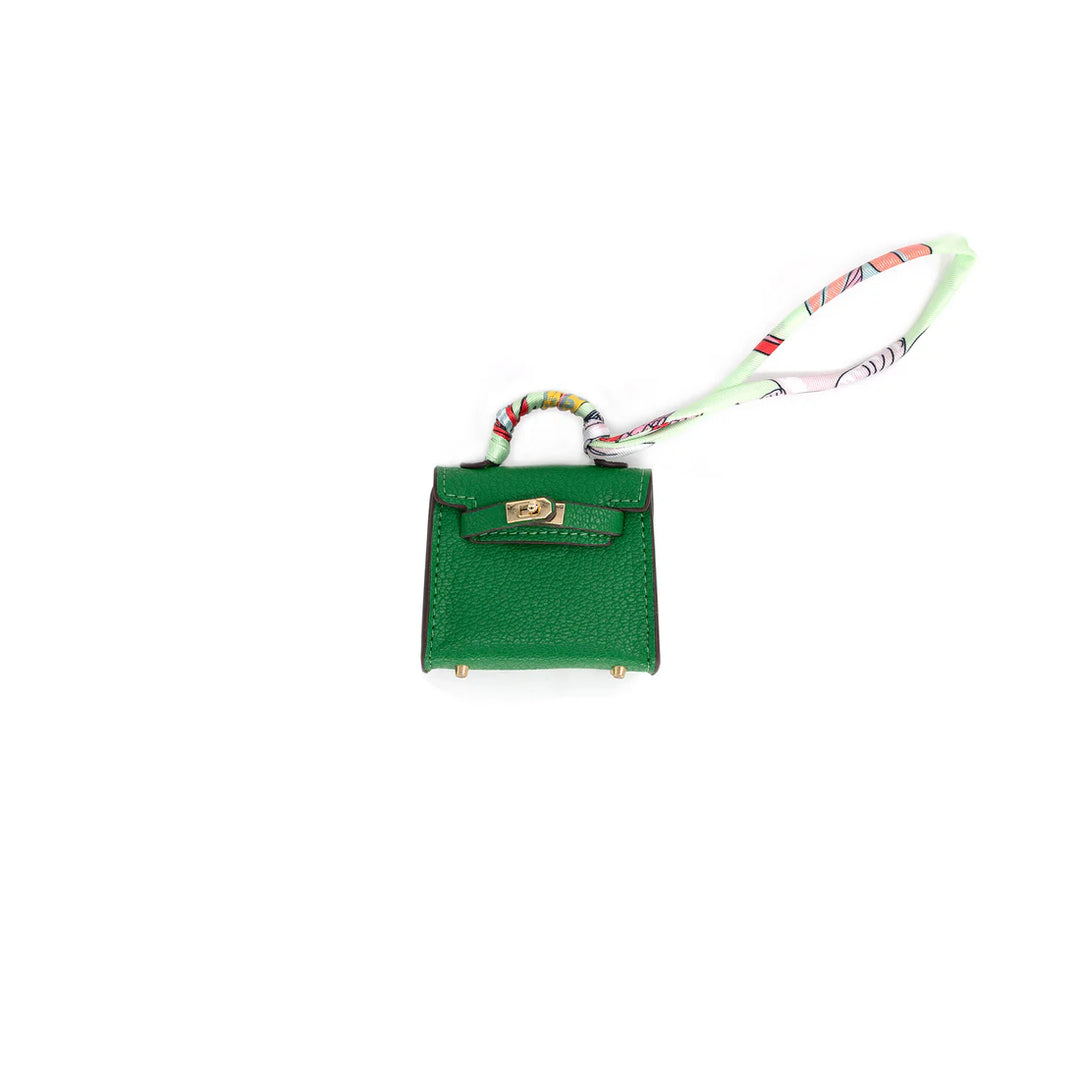 Green handbag charm with a strap on a white background
