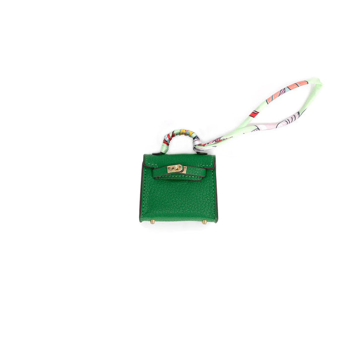 Green handbag charm with a strap on a white background