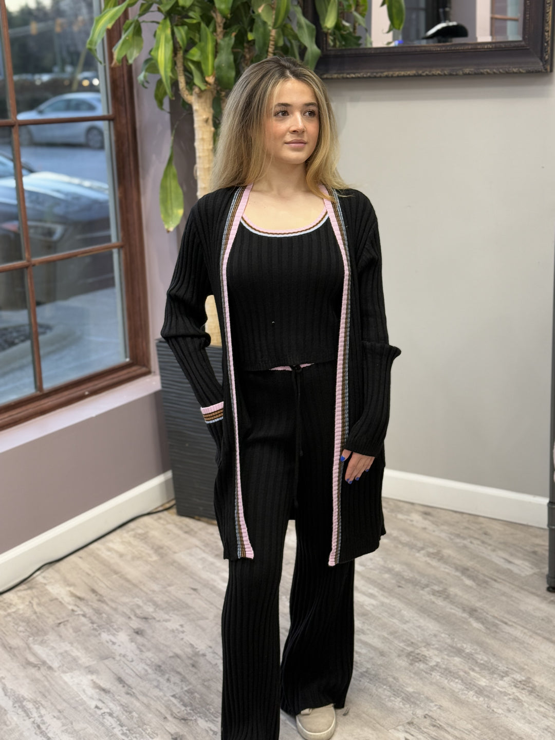 Women's ribbed lounge set in black, featuring a long cardigan with lavender trim, a cropped tank top, and matching wide-leg pants. Perfect for cozy, stylish relaxation.