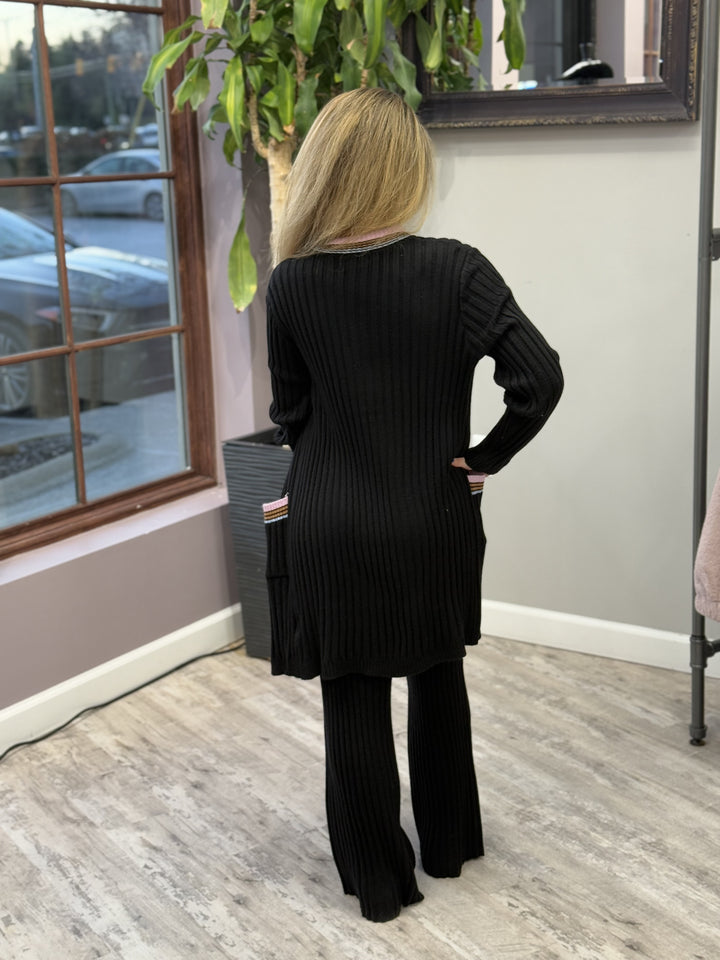 Women's ribbed lounge set in black, featuring a long cardigan with lavender trim, a cropped tank top, and matching wide-leg pants. Perfect for cozy, stylish relaxation.