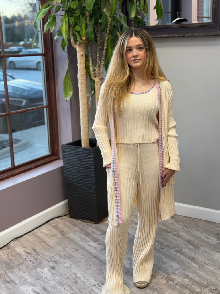 Women's ribbed lounge set in cream, featuring a long cardigan with lavender trim, a cropped tank top, and matching wide-leg pants. Perfect for cozy, stylish relaxation.