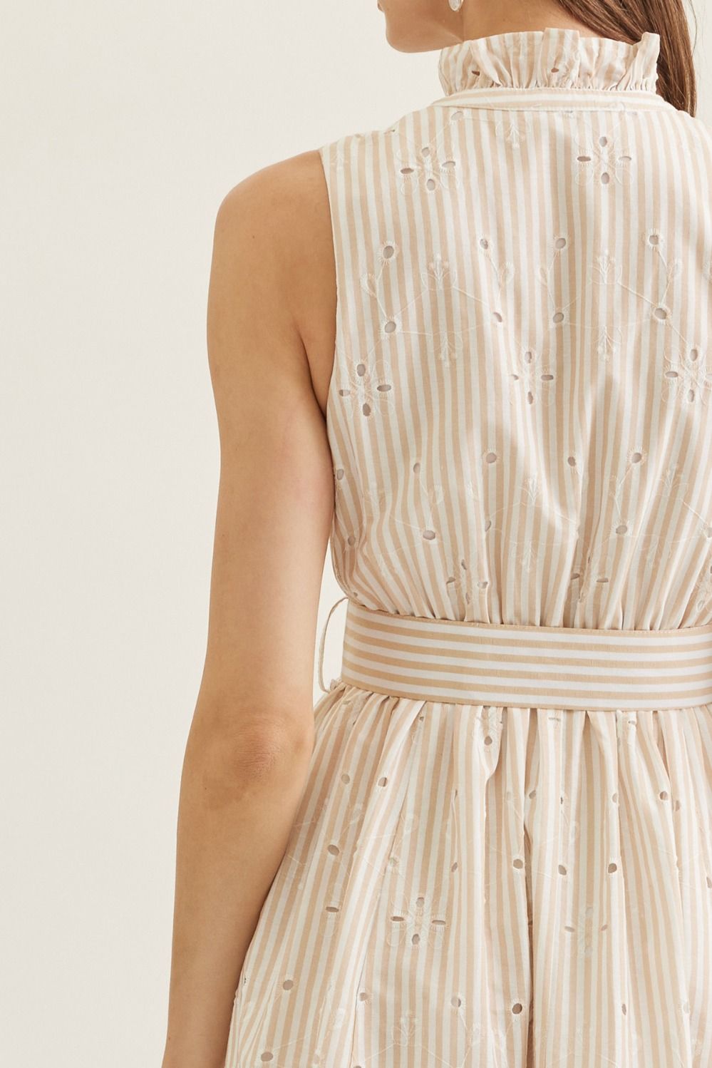 Beige striped dress with a belt on a plain background
