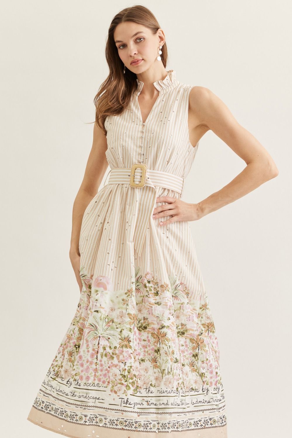 Woman wearing a sleeveless dress with floral pattern and belt on a plain background