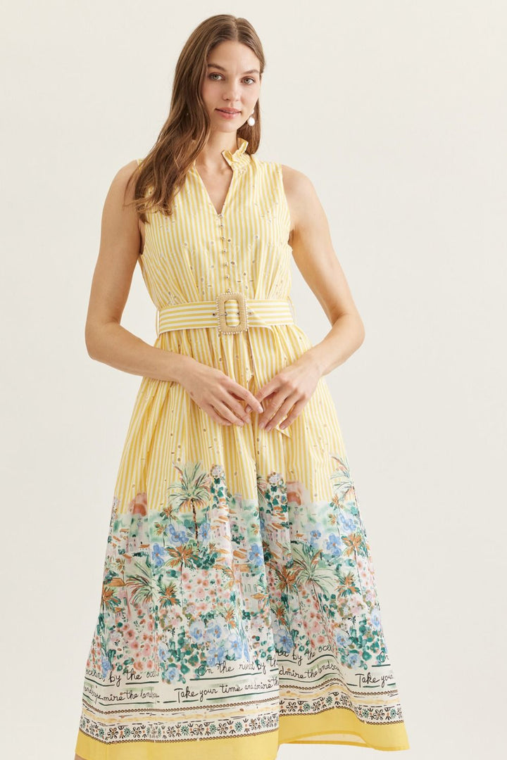 Woman wearing a yellow dress with floral pattern on a plain background