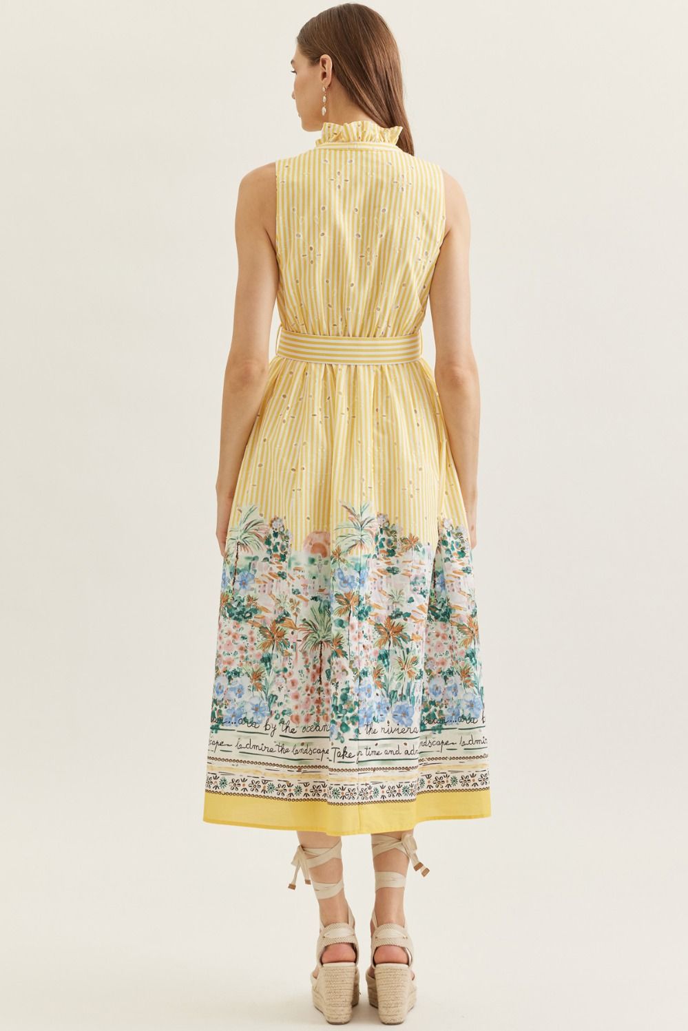 Woman wearing a yellow dress with floral pattern on a white background