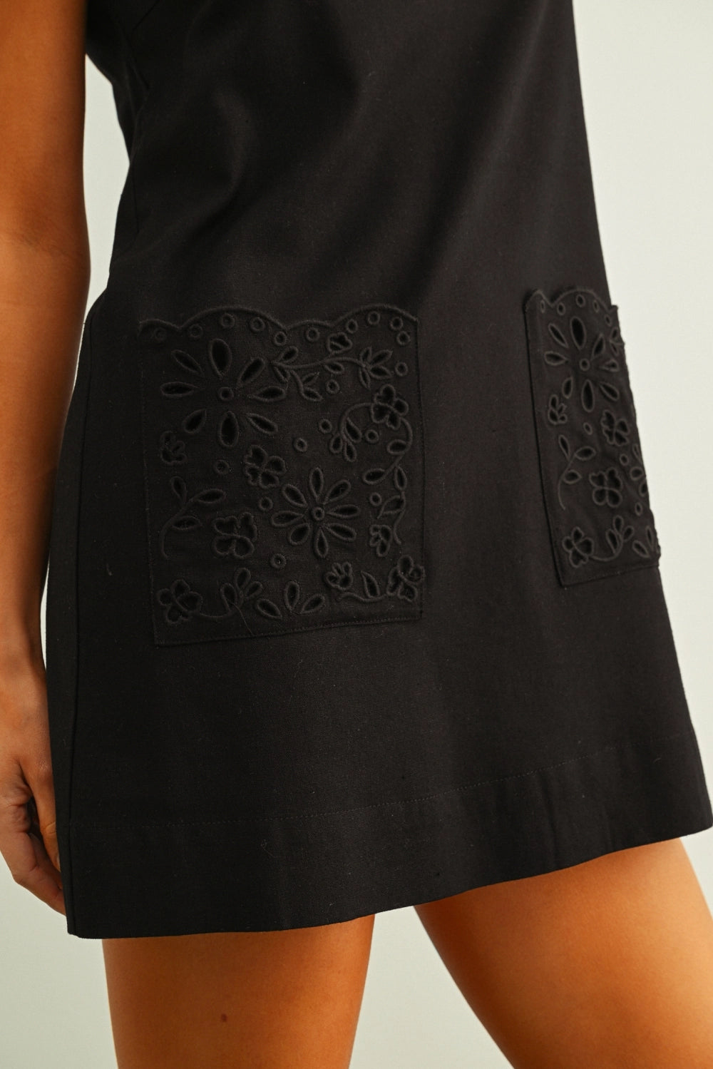 Black dress with decorative cut-out panels on a neutral background