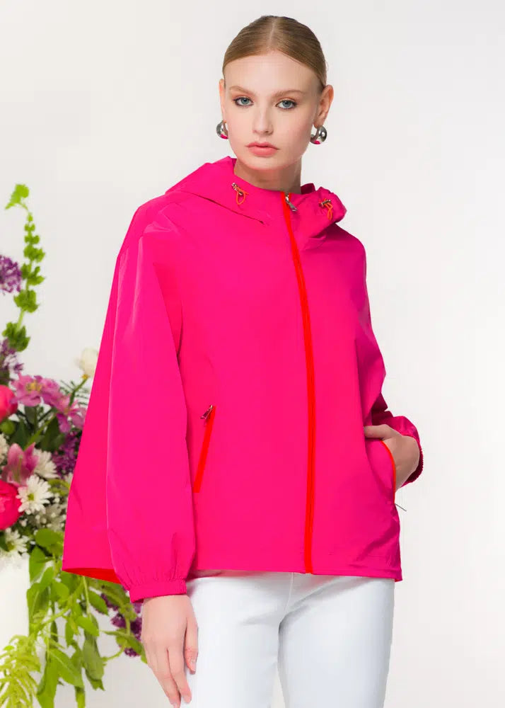 Woman wearing a bright pink jacket with a white background