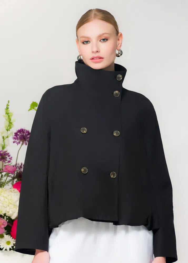 Woman wearing a black coat with gold buttons against a white background