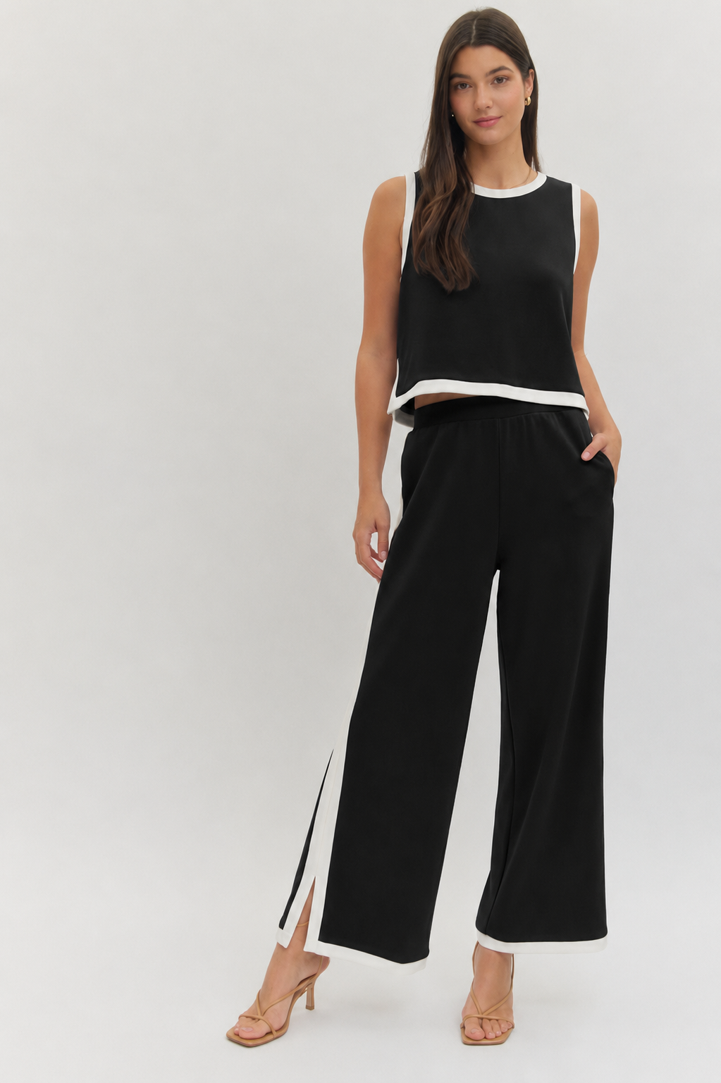 Woman wearing a black sleeveless top and wide-leg pants on a white background