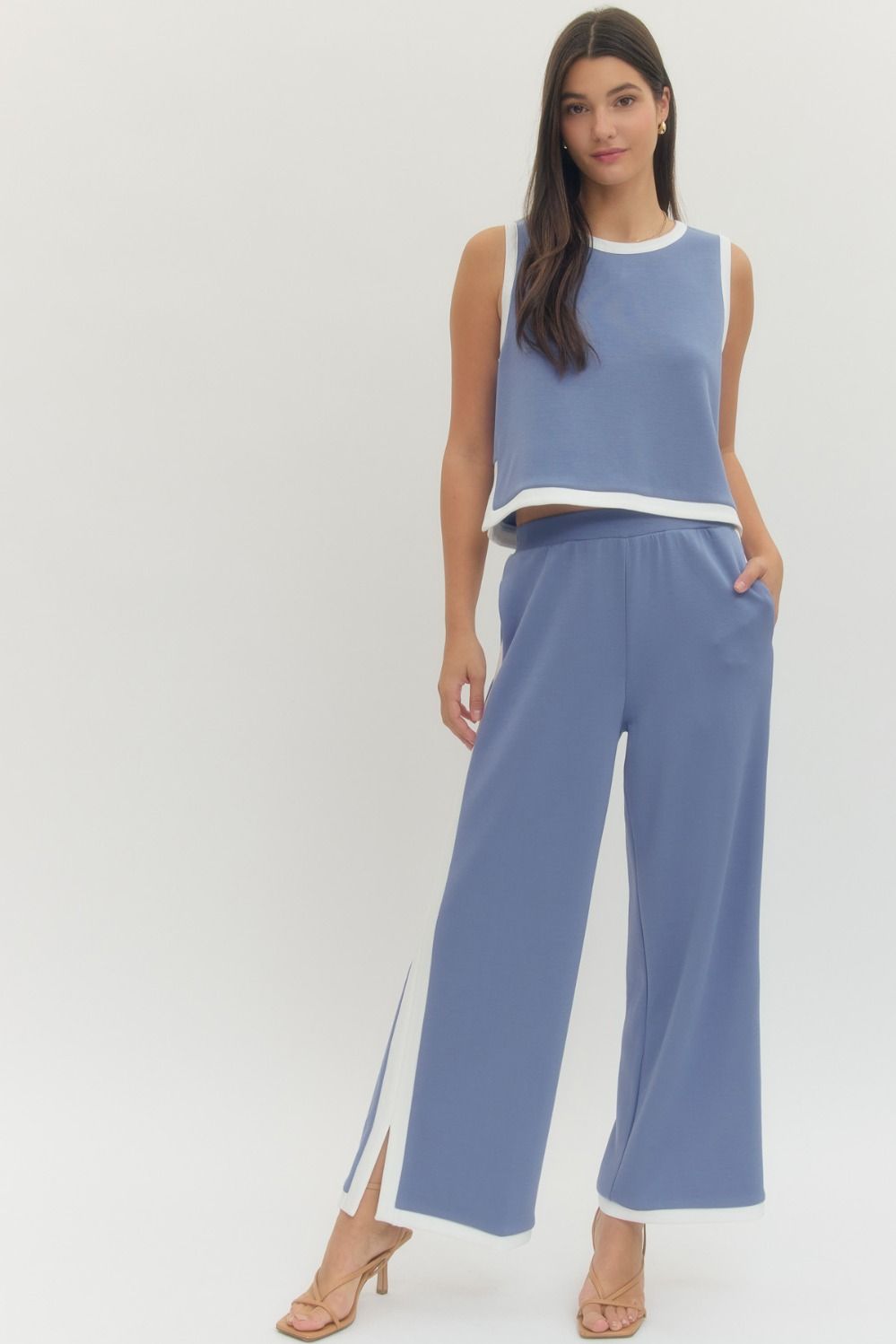 Woman wearing a blue sleeveless top and wide-leg pants on a white background
