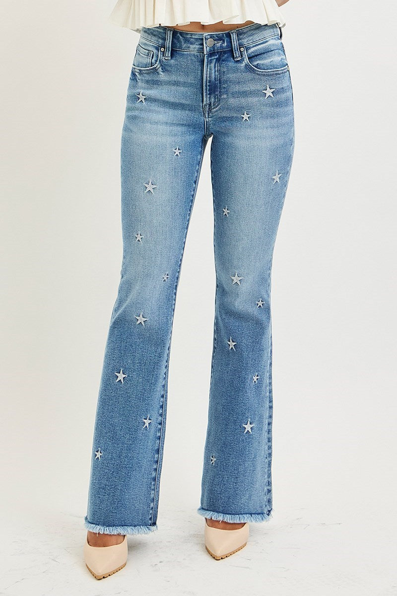 Blue jeans with star embellishments on a light gray background