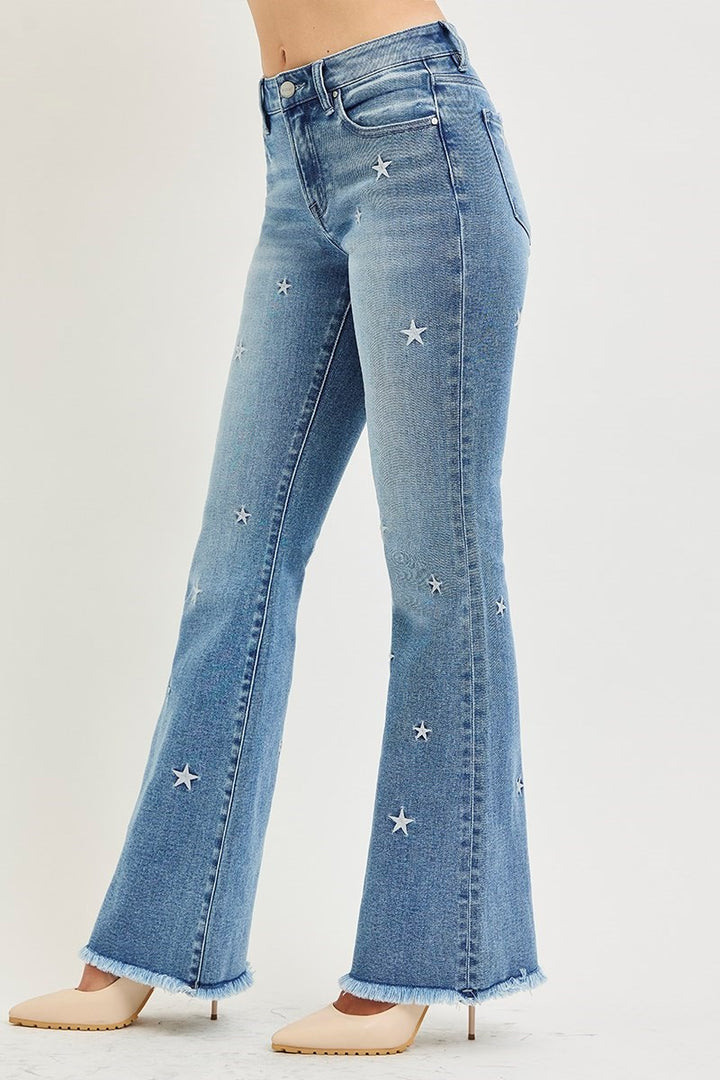 Blue jeans with star embellishments on a light gray background