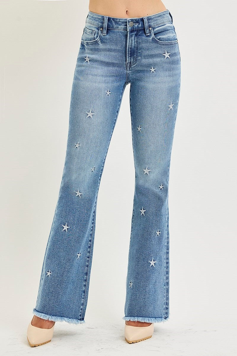 Blue jeans with star embellishments on a light gray background