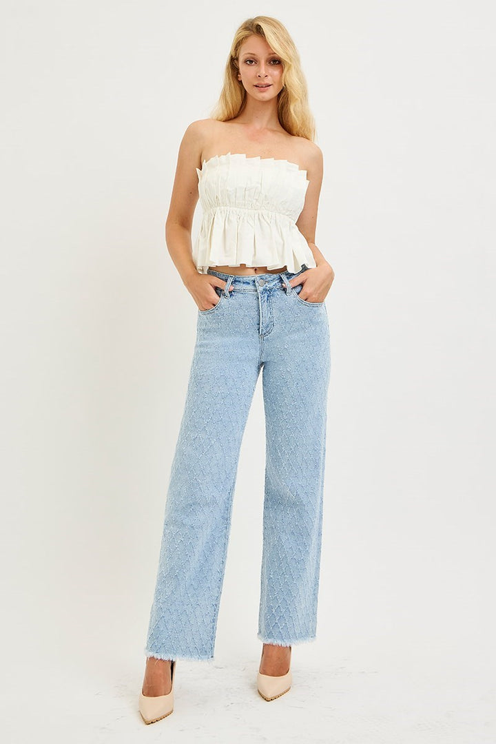Woman wearing a white strapless top and light blue jeans on a white background
