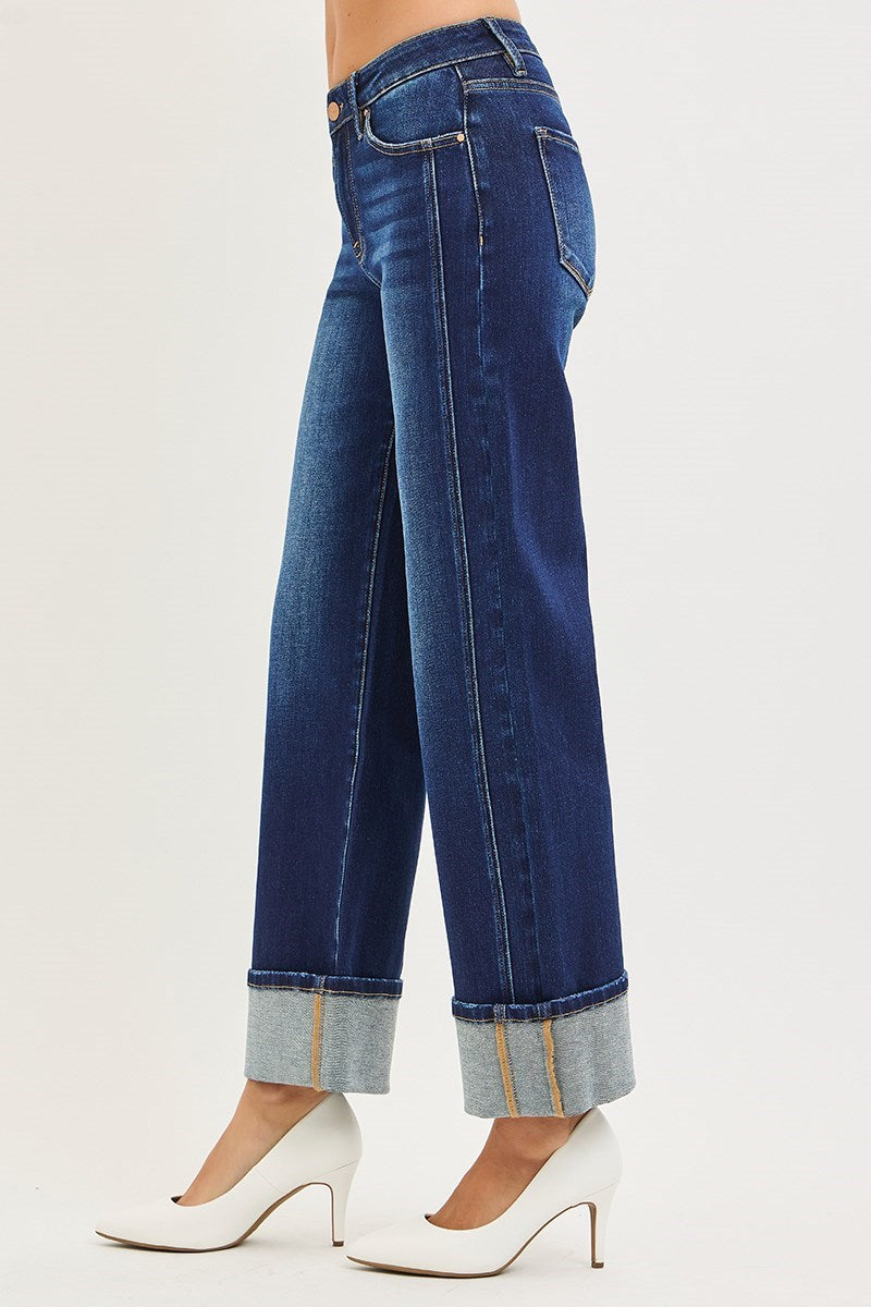 Blue jeans with rolled-up cuffs worn by a person on a white background