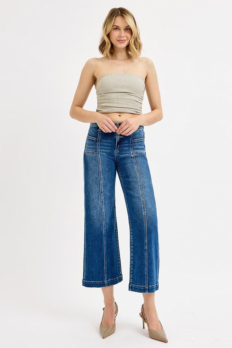 Woman wearing a strapless top and wide-leg jeans on a white background