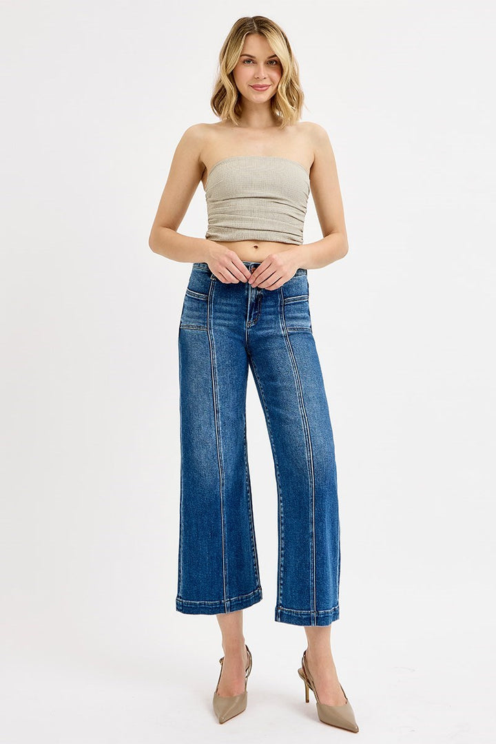 Woman wearing a strapless top and wide-leg jeans on a white background