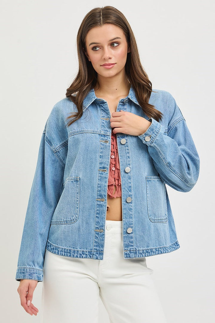 Woman wearing a denim jacket over a pink top on a white background