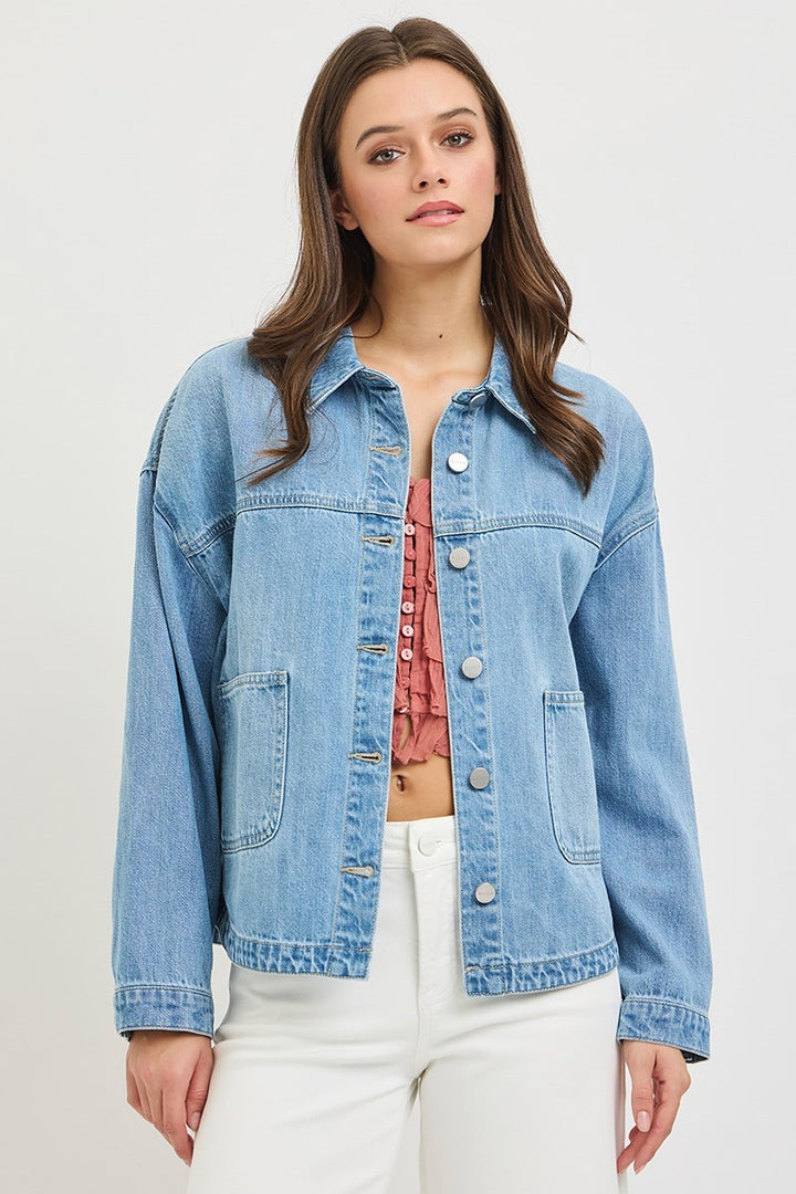 Woman wearing a light blue denim jacket on a plain background