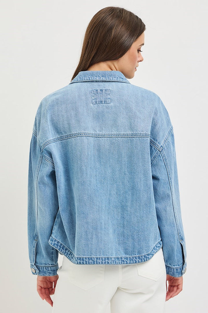 Woman wearing a light blue denim jacket on a white background