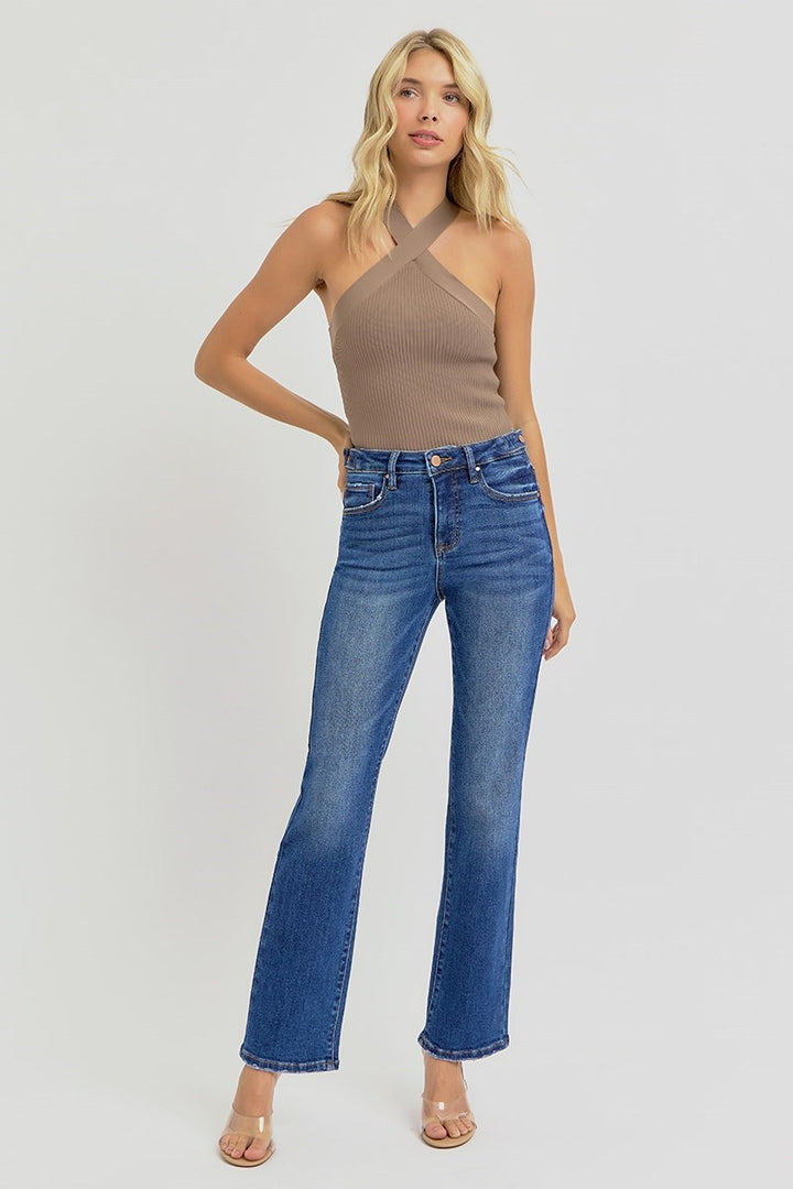 Woman wearing a brown halter top and blue jeans on a white background