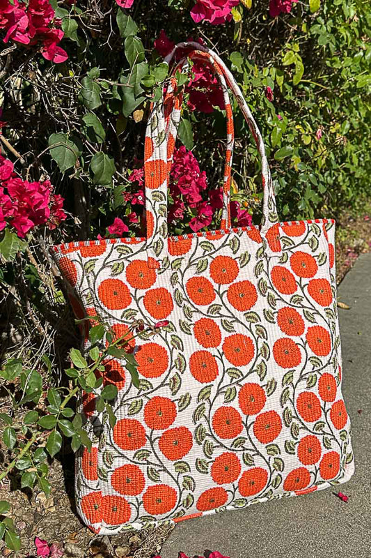Tote bag with orange floral pattern on a background of green foliage and pink flowers