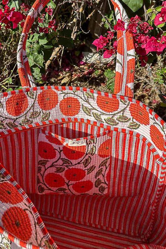 Red and white patterned fabric basket with floral design against a natural background