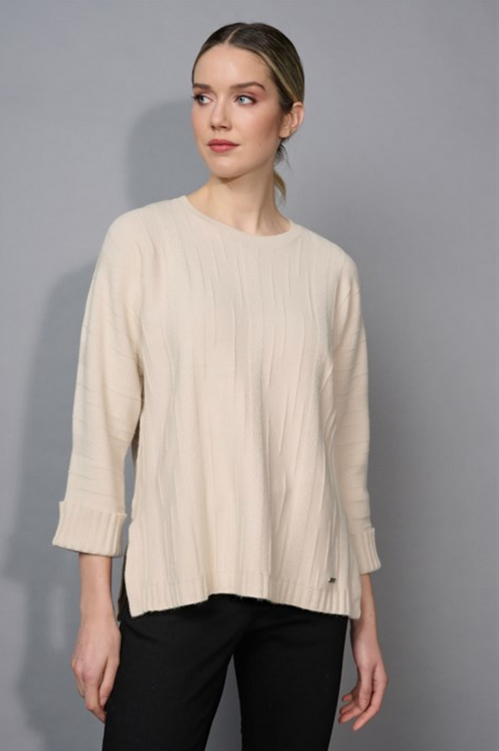 Woman wearing a beige sweater against a gray background