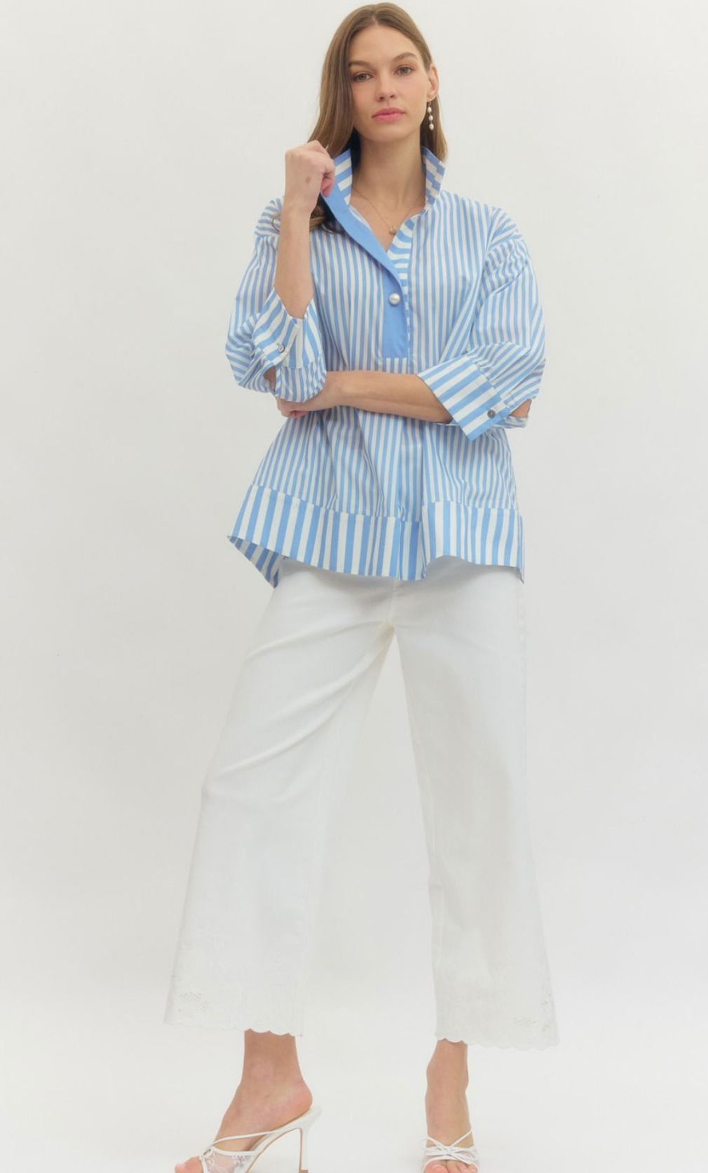 Woman wearing a blue and white striped shirt with white pants on a white background