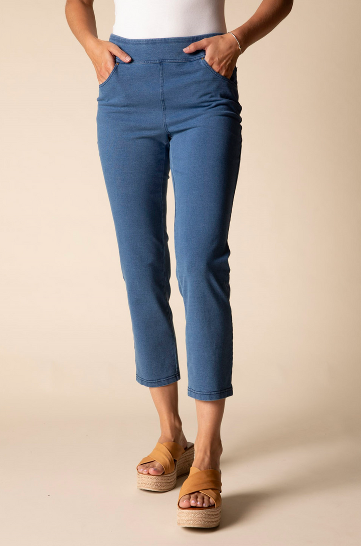 Person wearing blue pants and sandals on a beige background