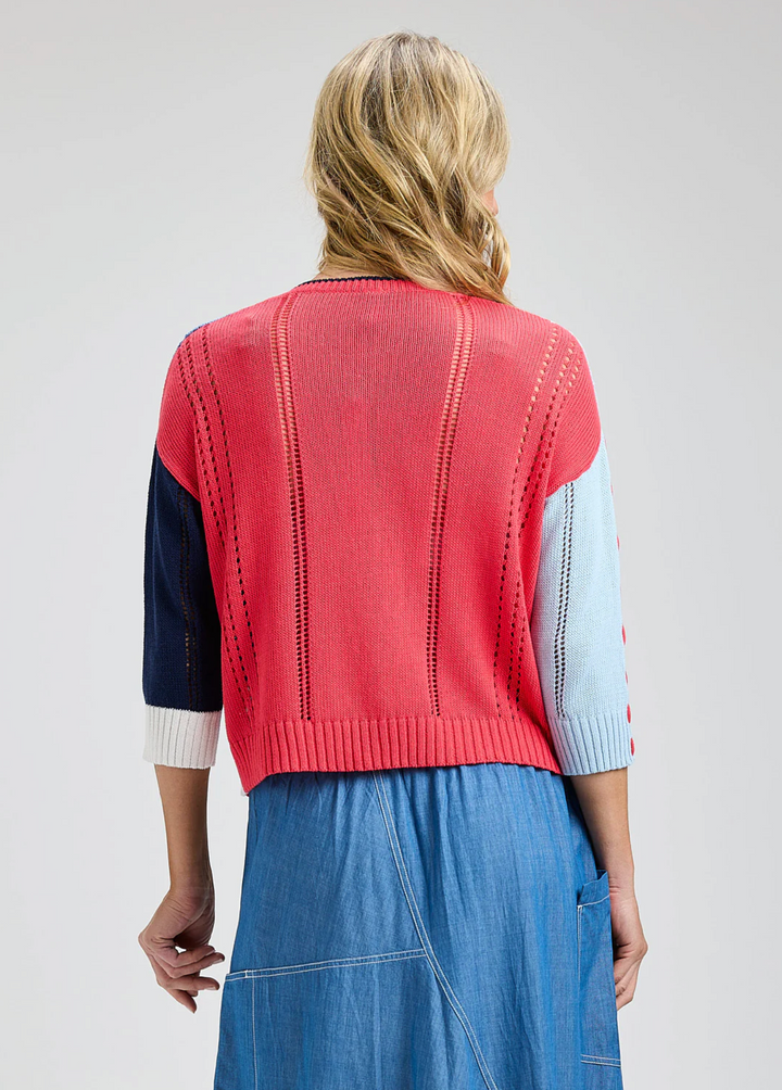 Person wearing a red sweater over a blue dress with a white background