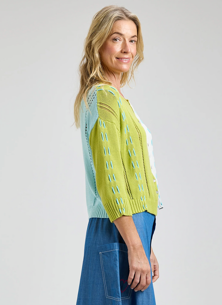 Woman wearing a green and blue patterned top with a plain background