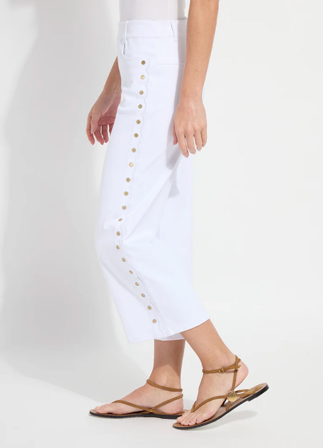 White pants with gold buttons worn by a person on a white background