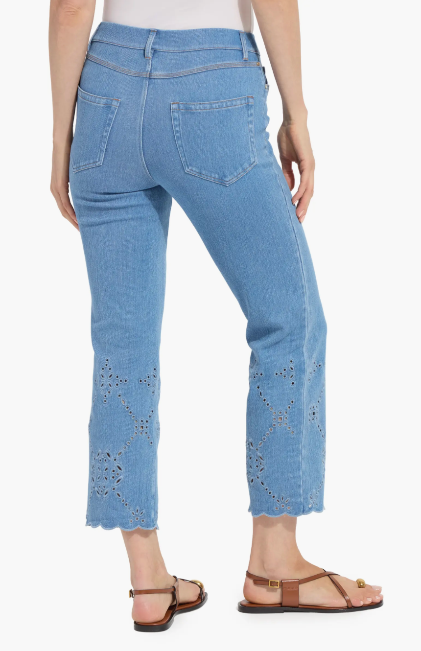 Light blue jeans with eyelet details worn by a person on a white background