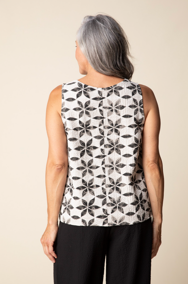 Person wearing a sleeveless top with a black geometric pattern on a beige background