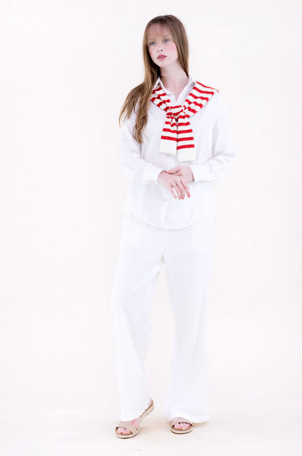Woman wearing a white outfit with a red and white striped scarf on a white background