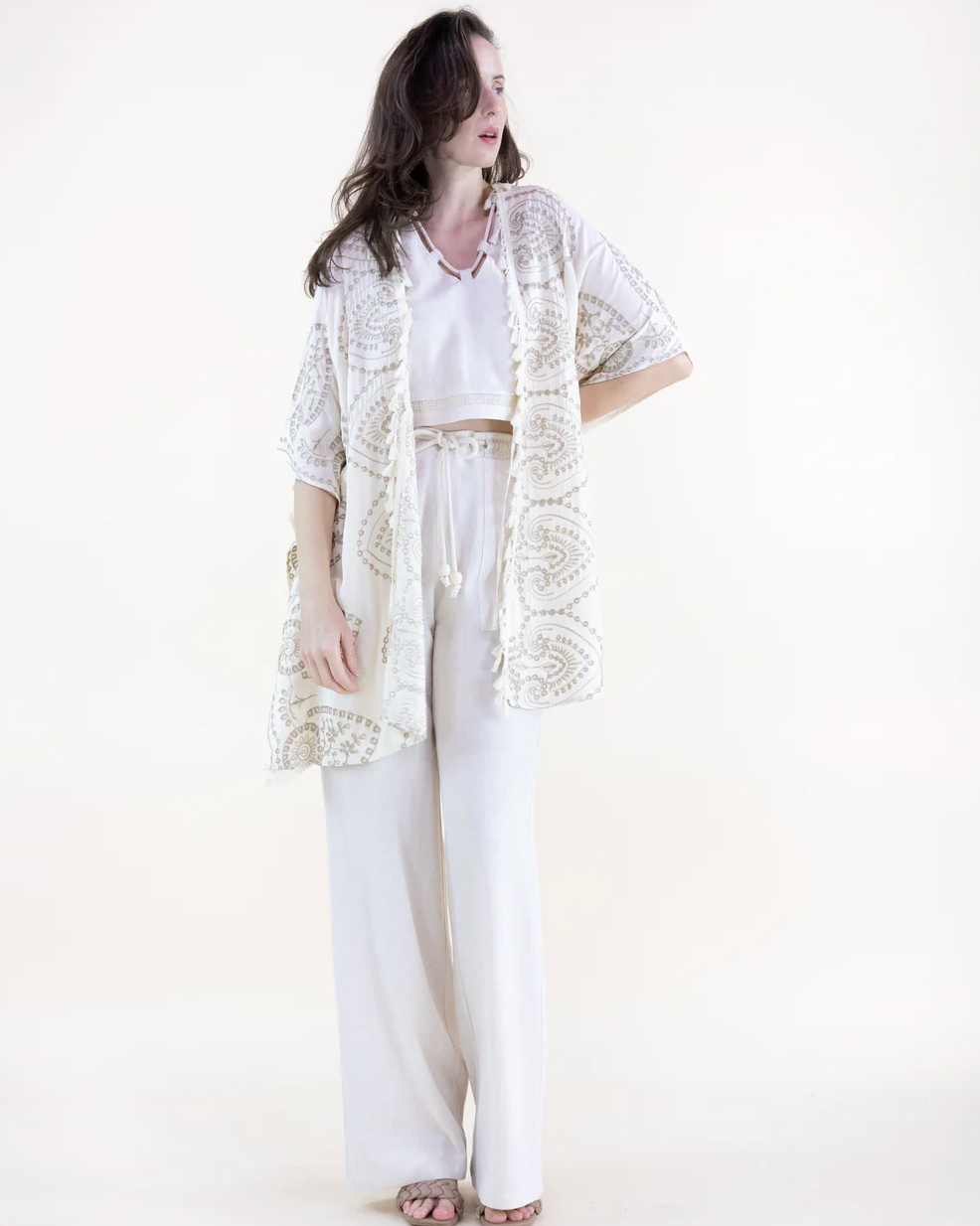Woman wearing a white lace kimono over a white outfit on a white background